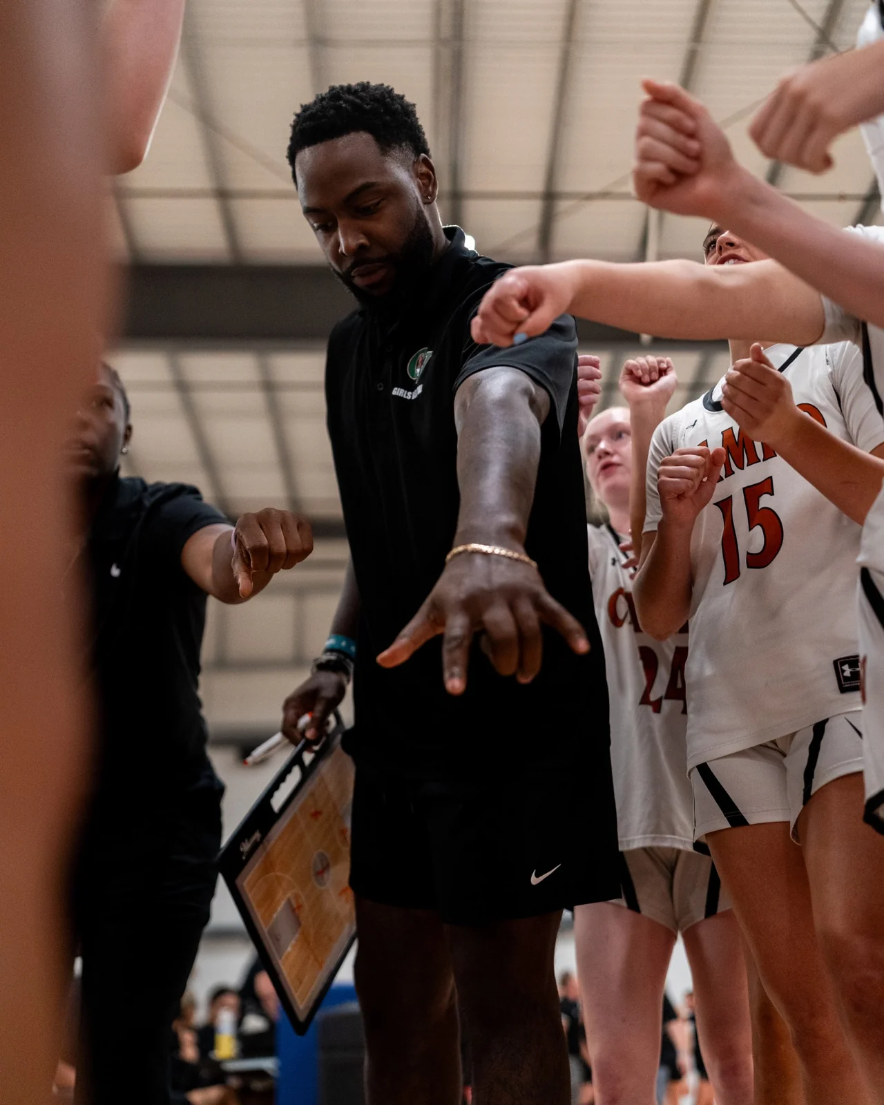 A basketball coach brings his team together in a huddle